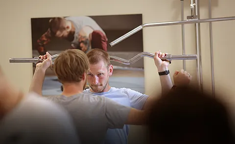 Patient trainiert unter physiotherapeutischer Anleitung in der medizinischen Trainingstherapie